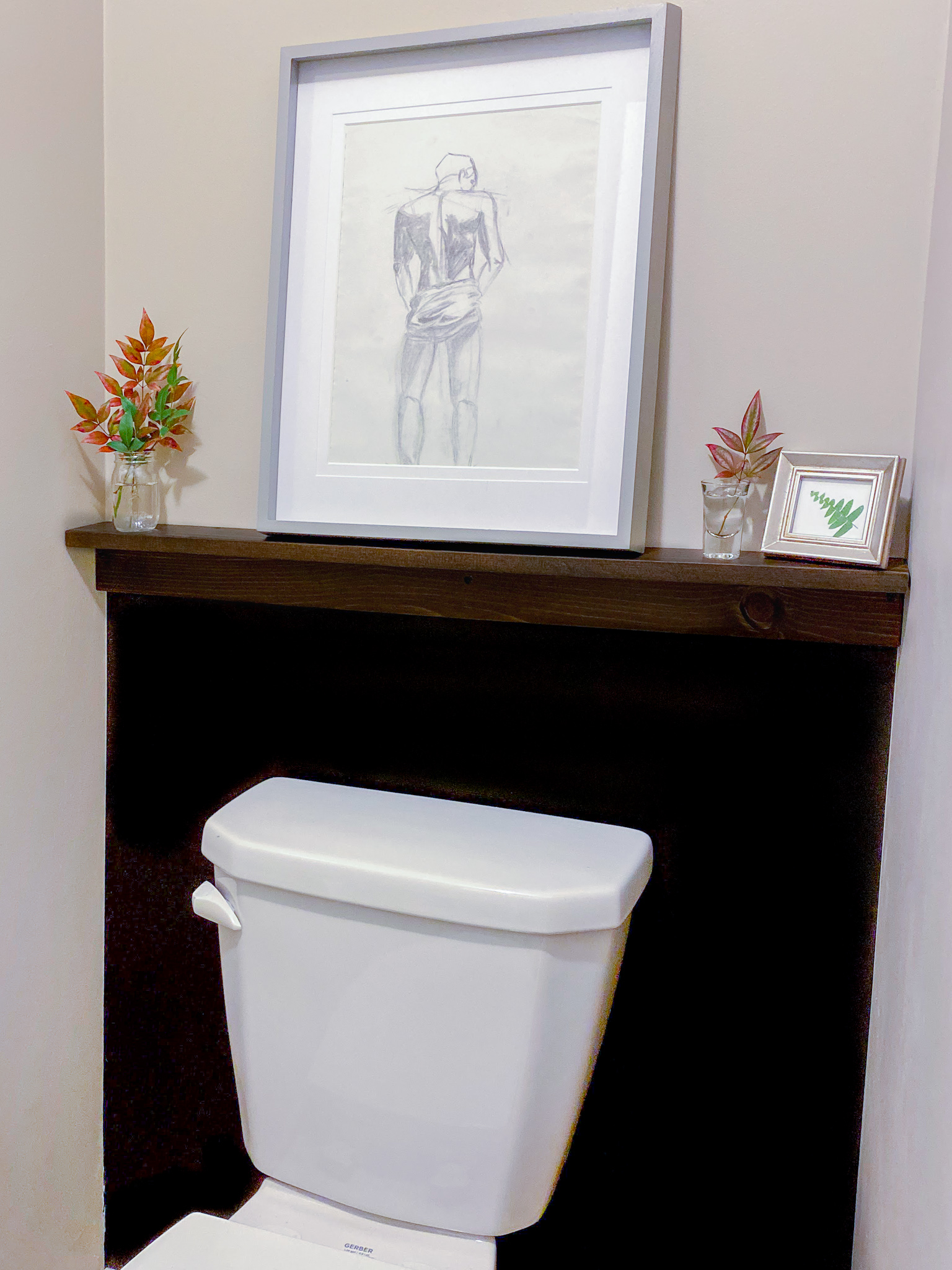 Small water closet with black, color blocked wall and walnut shelf.