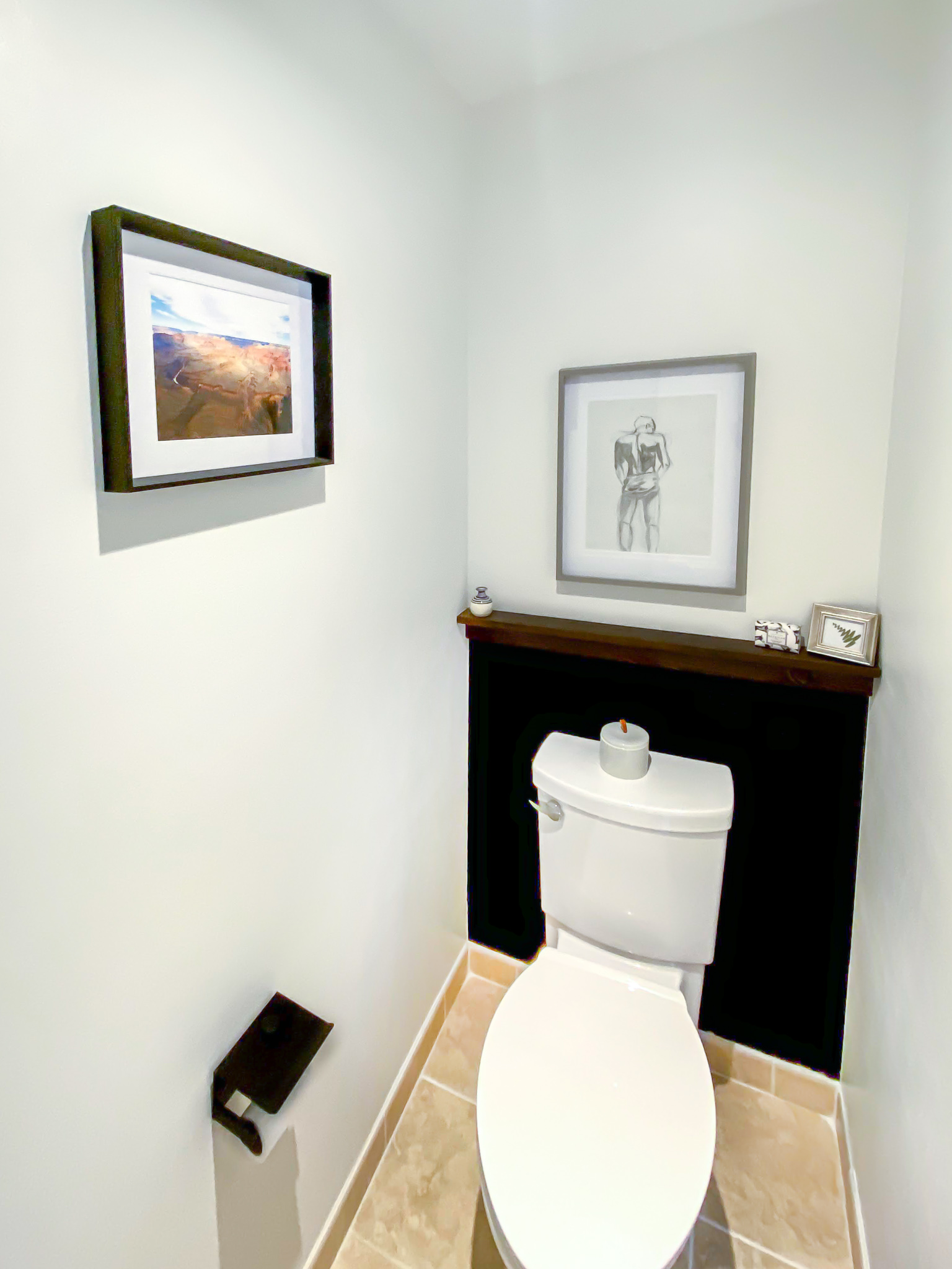 Small water closet with black, color blocked wall and walnut shelf.