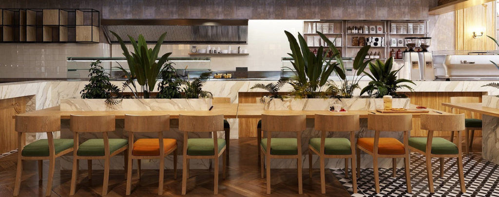 Neutral restaurant interior with wooden tables and lush, plant centerpieces.